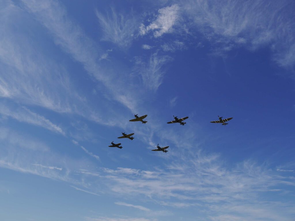 Spitfires and Hurricane fly over the airfield