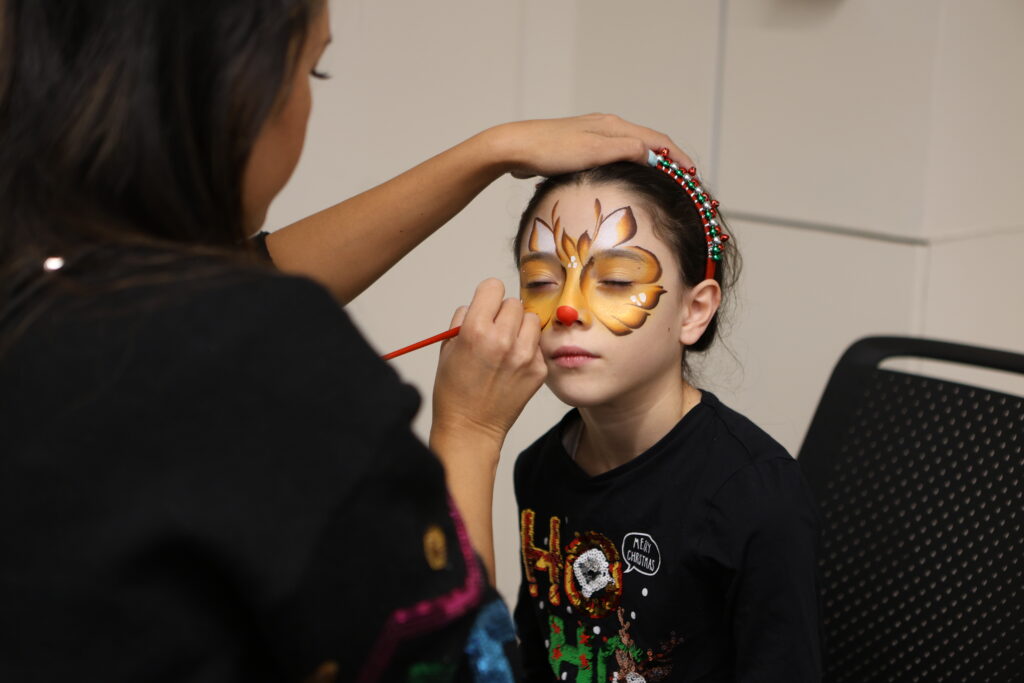 A woman face painting a butterfly