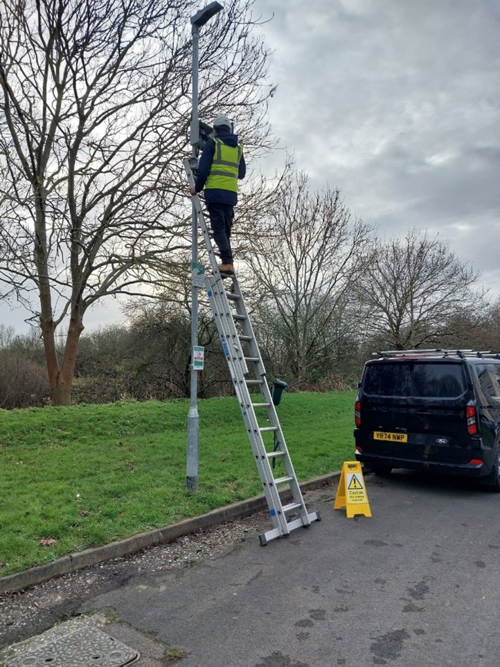 Person up a ladder making adjustments to lighting in Oakwood Hill estate